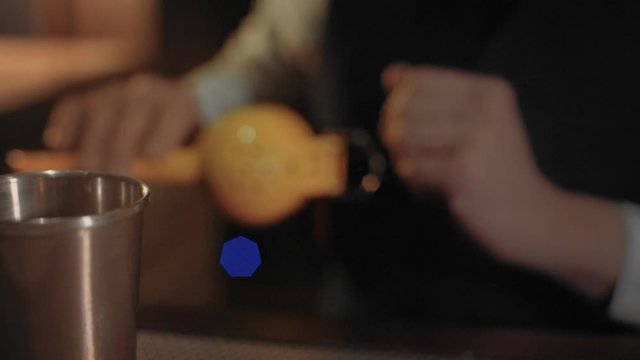 Close focus on bartender is squeezing lemon juice in shaker with special tool to make bespoke cocktail in stylish bar. Professional bar business lifestyle concept
