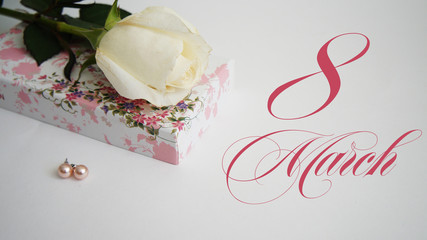 greeting card, White rose, earrings and casket on a white background the inscription "March 8"