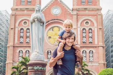 Father and son in the background Notre dame de Saigon Cathedral, build in 1883 in Ho Chi Minh city, Vietnam