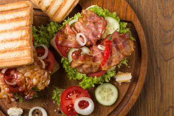 Toasted sandwich with bacon, tomato, cucumber and lettuce.