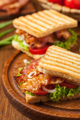 Toasted sandwich with bacon, tomato, cucumber and lettuce.