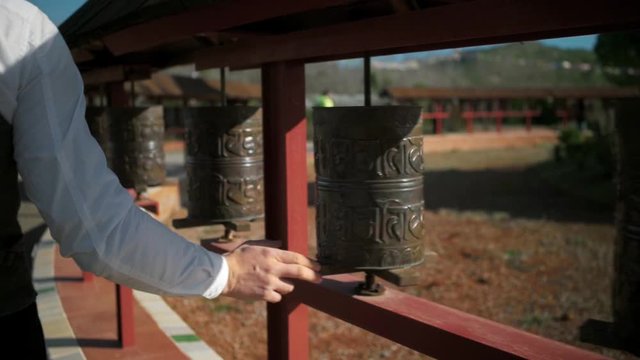 Businessman or office clerk worker turns buddhist prayer wheel, asking gods and spirits for luck and success in new venture or startup idea. concept superstition
