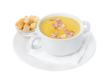 Soup puree, cream soup yellow with ham and croutons, dry bread. On a napkin in a white plate isolated white. Serving dishes in a cafe, restaurant, for a menu. Side view