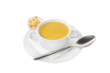 Soup puree, cream soup yellow with crackers, dry bread and a spoon. On a napkin in a white plate isolated white. Serving dishes in a cafe, restaurant, for a menu. Side view