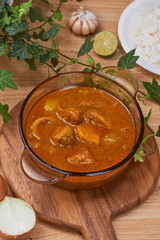 Tasty dinner with chicken curry in bowl on wooden background