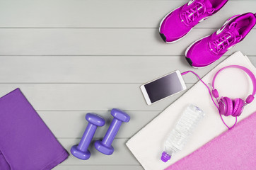 Sport and fitness accessories, healthy and active lifestyle concept on wooden floor background with copy space. Products with vibrant, punchy pastel colours. Image taken from above, top view.