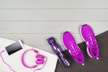 Sport and fitness accessories, healthy and active lifestyle concept on wooden floor background with copy space. Products with vibrant, punchy pastel colours. Image taken from above, top view.