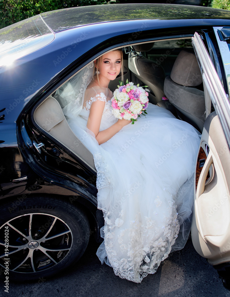 Wall mural happy charming bride sits in the black car - Wall murals