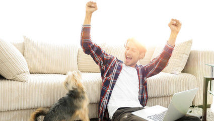 happy young man exults with his dog sitting in the living room