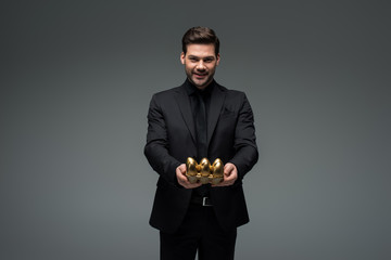 Smiling man with golden eggs isolated on grey, easter concept