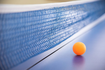 Orange ball for tennis on a blue table with a grid
