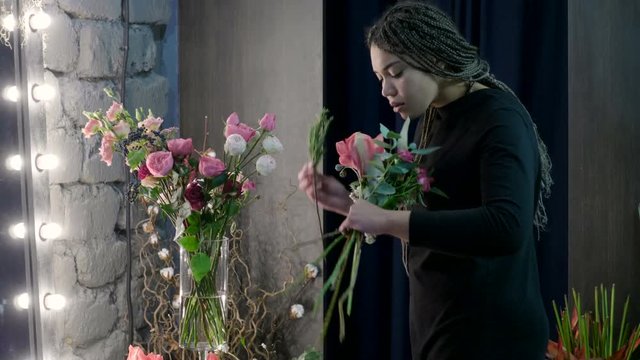 Female afro-american florist making a bouquet of fresh flowers in a florist's. 4K
