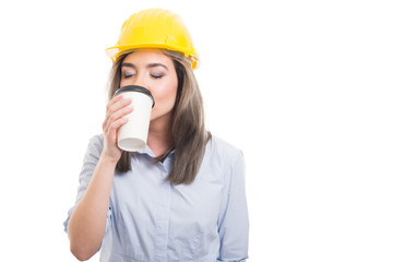 Pretty female constructor drinking takeaway coffee.