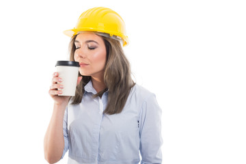 Pretty female constructor smelling takeaway coffee.