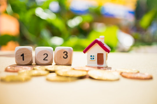 Miniature house with wooden block number and stack coins using as property and financial concept