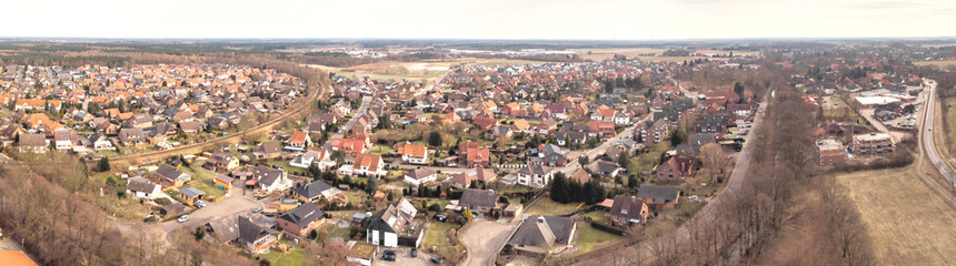 Fototapeta na wymiar Composite panorama of aerial photographs and aerial photos of a small village in the heath in Northern Germany with meadows, fields and houses, above the roofs.