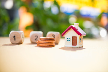 Miniature house with wooden block number and stack coins using as property and financial concept