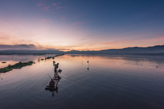 Fisherman works on bamboo raft in early morning