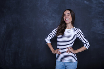 Portrait of a happy thoughtful woman looking on camera with copyspace over blackboard background