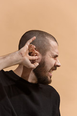 The Ear ache. The sad man with headache or pain on a pastel studio background.