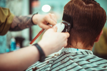 Men's haircut in barbershop. Hair care. Tinted photo. Soft focus.