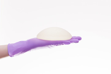 Silicone breast implant on hands. Doctor tries on silicone breasts
