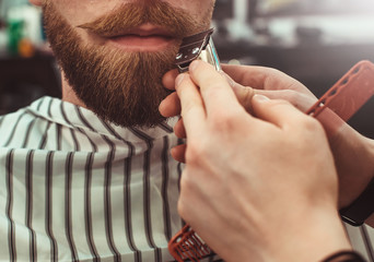 Details of trimming. Cropped closeup of a barber trimming beard to his client