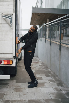 Full length of man talking through mobile phone while pushing button on delivery van