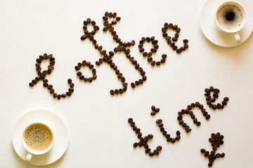 Two cups of espresso and Coffee time text from beans on white table. Top view