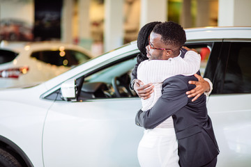 Smiling couple hugging and smiling at camera at new car showroom © alfa27