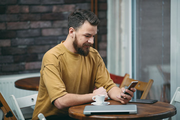 Young man sitting in cafe and using smart phone.