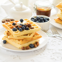 Healthy breakfast. Belgian waffles with butter, blueberry and nuts on white tablecloth. Selective focus
