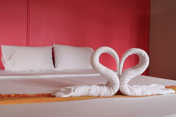 Towel heart shape white color decorate on bed love design  romantic at room hotel wall pink background