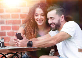 Lovely young couple looking at smart phone at cafe
