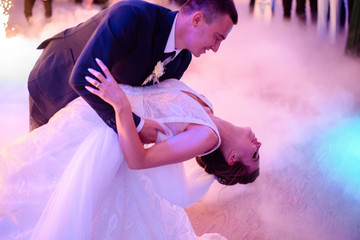 Groom whirls bride while they dance in a smoke for the first time
