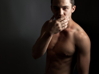 Fototapeta premium Handsome athletic guy with a naked torso on a black background