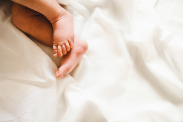 Tender feet of a newborn baby lying on white blanket
