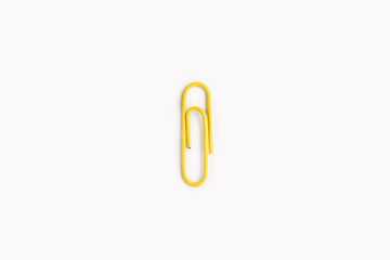 Obraz premium Yellow paper clip on a white background.