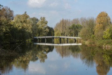 White bridge over the water in the sunny autumn day with yellow trees around it