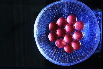 Close up transparency colorful jelly balls on glass dish on black background
