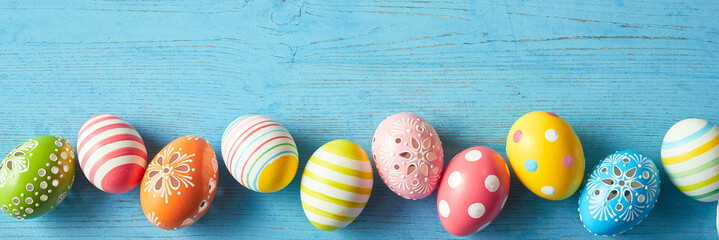 Border of colorful decorated Easter eggs on blue