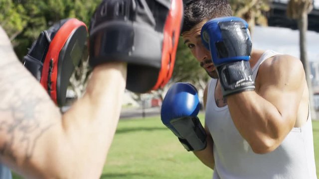Young strong male boxing training in the sunshine, in slow motion