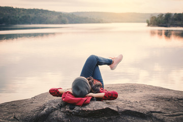 Relaxing moment Asian tourist sleeping on rock waiting for sunset ,enjoying time on holiday concept...