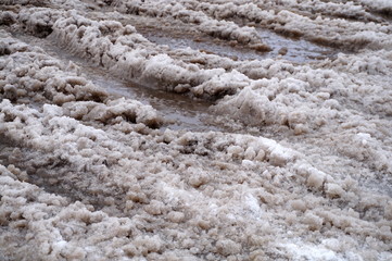 The snow melts on the road and turns into a puddle and slush in the city