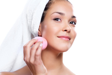 Beautiful woman cleaning face with a sponge.