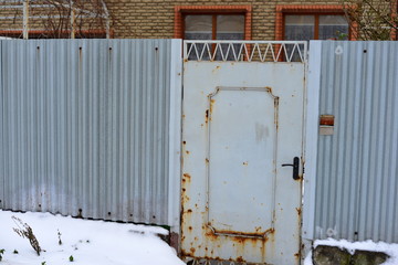 Rusty iron fences with gates on the street, guarding the private territory.