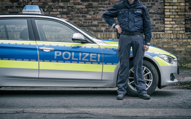 Polizist neben Polizeiauto (Deutschland)