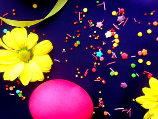 Easter background on purple with bright bokeh effect. Instagram effect. Multicolored eggs, ribbons, yellow chrysanthemums and sprinkling. Copy space