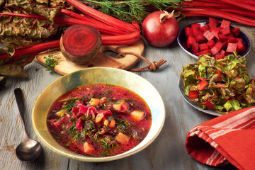 Spring food background: vegetable soup with beet root and fresh leaves