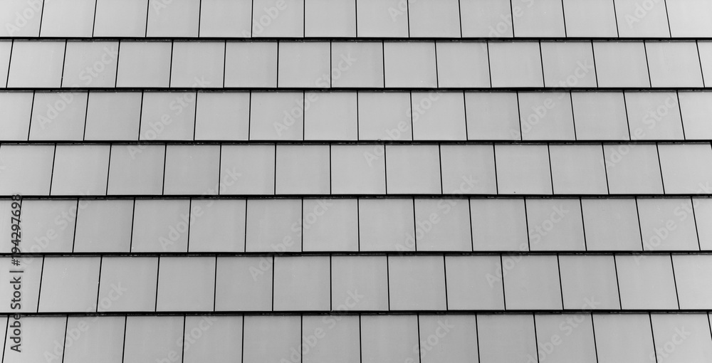 Poster a close-up of a roof with rows of grey rectangular tiles.